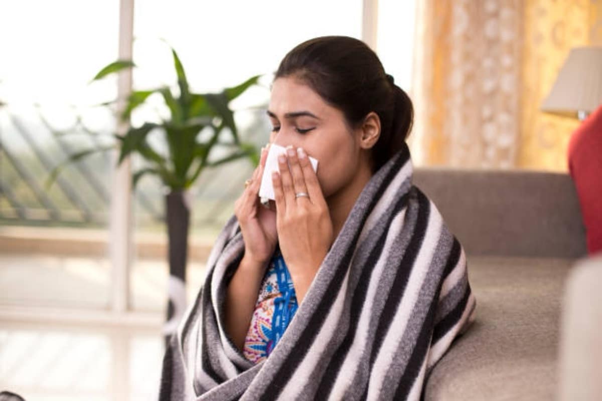 Sick woman sitting at home and blowing her nos